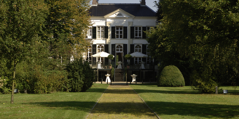 Landgoed het Laer bij Ommen met aan beide kanten hoge, groene bomen.