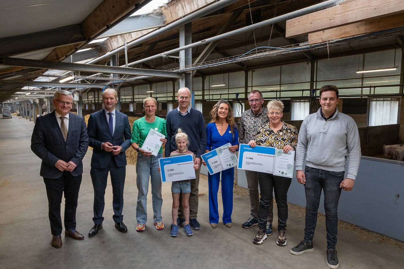 Groep mensen ontvangt de Waarde-Ring van gedeputeerden Gert Harm ten Bolscher en Maurits von Martels.