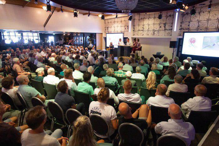 Een groep mensen woont een bijeenkomst bij in een grote zaal.