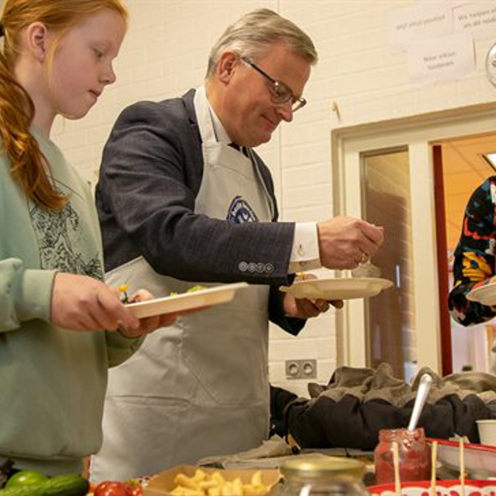 Gert harm ten Bolscher met schort en bord tussen vrouw en kind