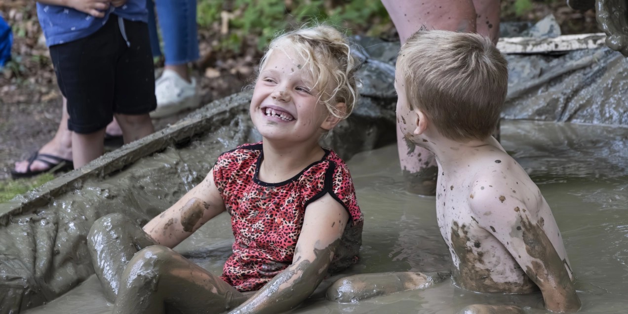 Twee kinderen hebben plezier in een modderbad.