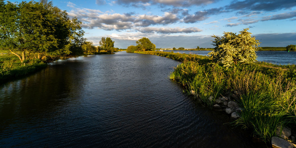 Foto van brede rivier met groene oevers