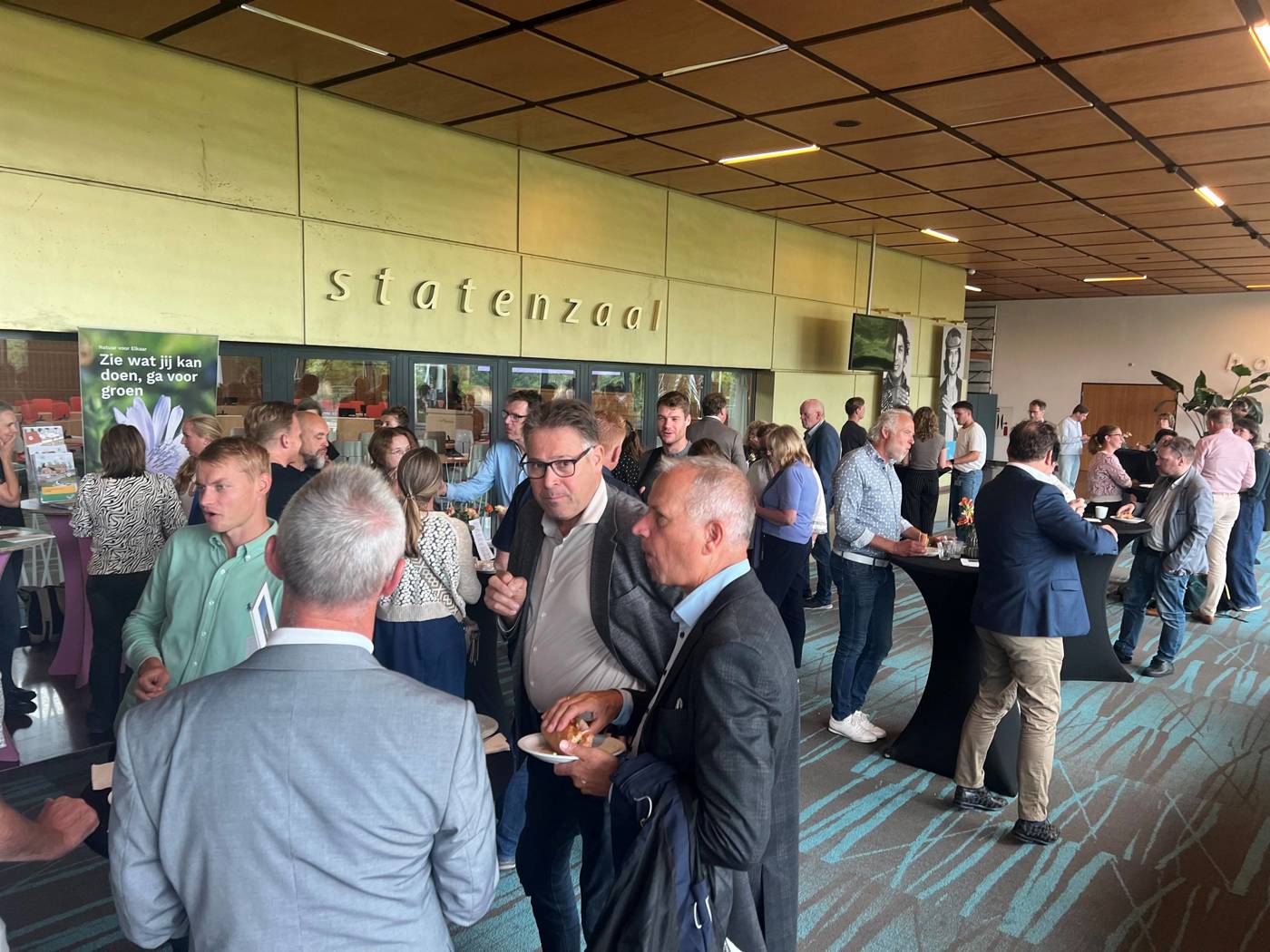 Mensen in de Statenzaal tijdens een netwerkevent met eten en drinken.