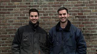 Laurens en Rutger Pelgrom poseren al lachend. Ze staan voor een bakstenen muur.